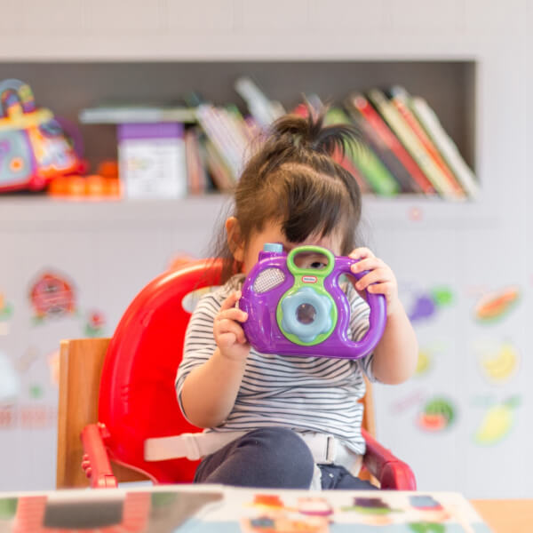 Toddler exploring a camera during preschool activity